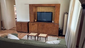 Een woonkamer met een groene bank, een houten salontafel en een flatscreen televisie op een houten kast.