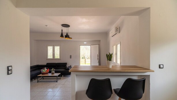A modern kitchen with a wooden countertop and two black bar stools.