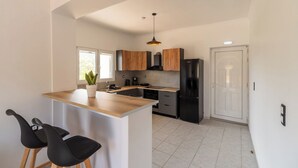 A modern kitchen with a wooden island, black appliances, and a white door.