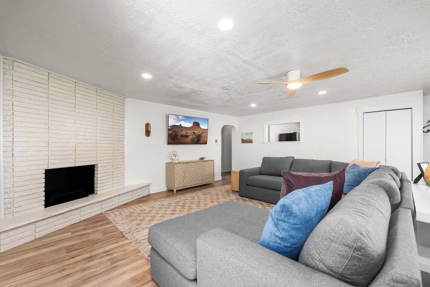 Ein Wohnzimmer mit Kamin, einer Couch, einem Fernseher und einem Deckenventilator.