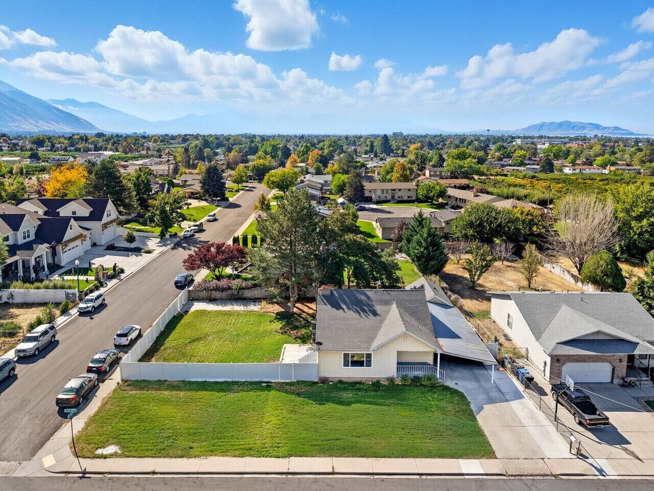 A residential area with houses, a parking lot, and a grassy field.