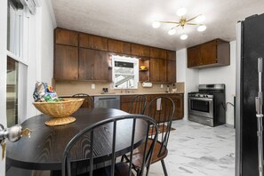 A modern kitchen with dark wooden cabinets, a stainless steel oven, and a dining area with a dark table and chairs.