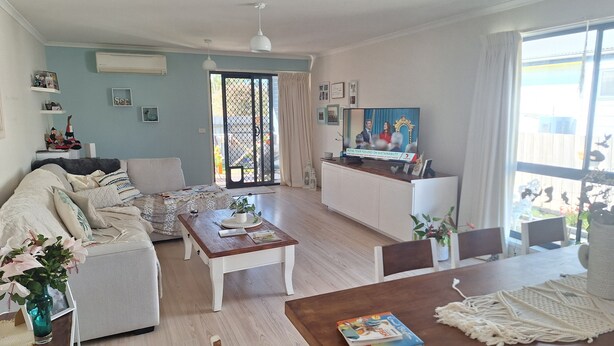 Una sala de estar con sofá, mesa de centro y mesa de comedor, televisor y balcón con vistas.