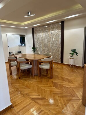 A conference room with a wooden table and chairs, a herringbone floor, and a patterned wall.