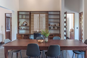 A dining area with a wooden table, six chairs, a vase with green plants, and a decorative wall with shelves. - Beautiful Spacious Apartment in the Heart of Santa Theresa (Santa Teresa)