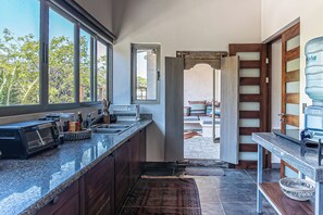 A kitchen with granite countertops, a toaster, and a water dispenser. - Beautiful Spacious Apartment in the Heart of Santa Theresa (Santa Teresa)