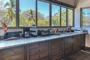 A kitchen with a large window, a toaster, a coffee maker, and a sink. - Beautiful Spacious Apartment in the Heart of Santa Theresa (Santa Teresa)