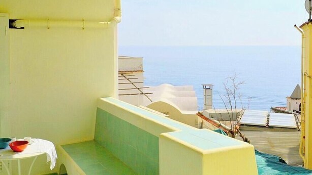 Ein Balkon mit Meerblick, einem Tisch mit einer Schale und einem Stuhl.