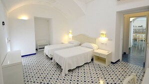 Ein Hotelzimmer mit zwei Betten, einem Nachttisch, einem Schreibtisch und einem Stuhl.