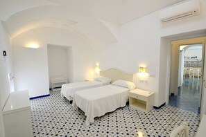 Habitación de hotel con dos camas, una mesita de noche, un escritorio y una silla.