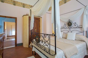Un lit à baldaquin, une armoire en bois et un miroir au mur.