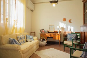 Un salon confortable avec un canapé, des fauteuils, un bureau et une cheminée.