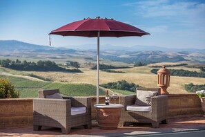 A patio with wicker furniture, a table with a bottle and glasses, and a red umbrella. - Villa in Fabbrica with 5 bedrooms sleeps 13 (Fabbrica)