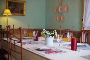 Une table à manger dressée avec des assiettes, des verres et un vase de fleurs.