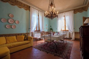 A dining area with a table set for four, a yellow sofa, and a chandelier. - Villa in Fabbrica with 5 bedrooms sleeps 13 (Fabbrica)