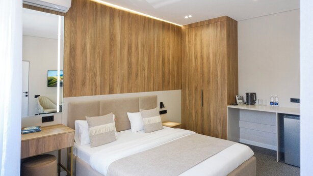 Ett modernt hotellrum med en stor säng, ett skrivbord och en garderob.