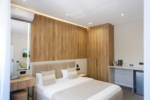 Ein modernes Hotelzimmer mit einem großen Bett, einem Schreibtisch und einem Kleiderschrank.