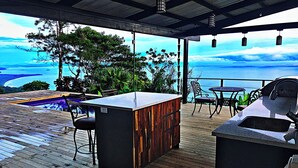 A wooden deck with a bar area, outdoor seating, and a view of the ocean. - Stunning Ocean View House with Pool, Outdoor Kitchen, and Rancho (Savegre de Aguirre)