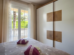 A hotel room with a bed, a sliding door, and a view of greenery outside. - Apartment in Porec Near Spadici Beach (Porec)