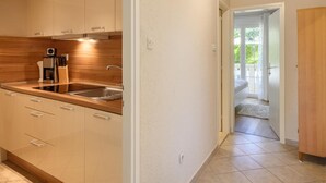 A modern kitchen with a built-in oven, a coffee maker, and a sink. - Apartment in Porec Near Spadici Beach (Porec)
