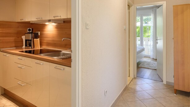 A modern kitchen with a built-in oven, a coffee maker, and a sink. - Apartment in Porec Near Spadici Beach (Porec)