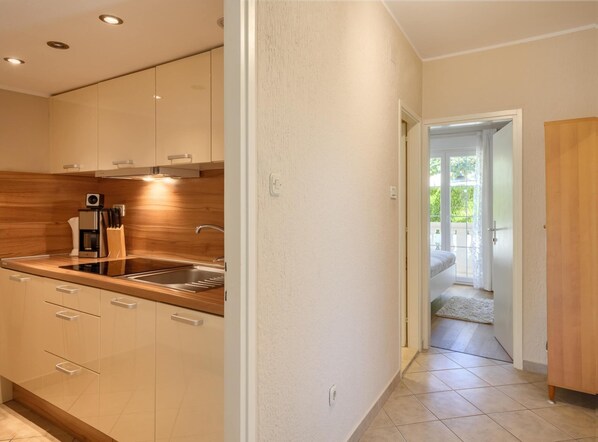 A modern kitchen with a built-in oven, a coffee maker, and a sink. - Apartment in Porec Near Spadici Beach (Porec)
