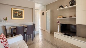 A modern living room with a dining area, a TV, and a painting on the wall. - Apartment in Porec Near Spadici Beach (Porec)