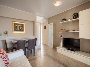 Un salon moderne comprenant un coin repas, un téléviseur et un tableau accroché au mur.