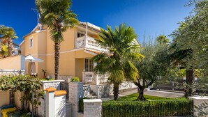 A Mediterranean-style building with a balcony, stone walls, and a well-maintained garden. - Apartment in Porec Near Spadici Beach (Porec)