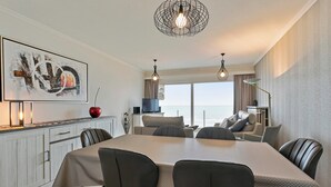 Een moderne eetruimte met een lange tafel, stoelen en een hanglamp.