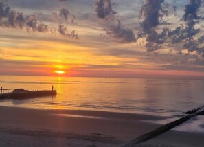 A sunset over a calm sea with a pier extending into the water. - Apartment in Blankenberge With Sea Views (Blankenberge)