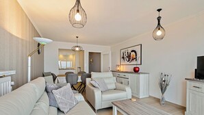 Een moderne woonkamer met een bank, fauteuil, salontafel en hanglampen.