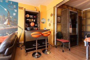 A modern kitchen with a bar area, a seating area with a sofa and chairs, and a cityscape mural on the wall. - Apartment in Ostend With Sea Views (Ostend)