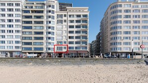 Un hôtel situé en bord de mer, avec plusieurs étages, des balcons et une plage de sable.