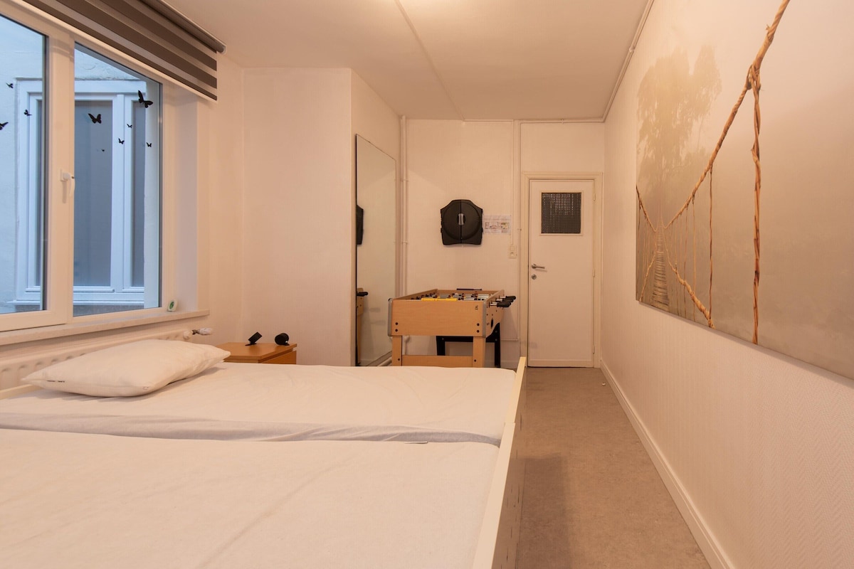 Ein Schlafzimmer mit Bett, Fenster, Tür und einem Wandregal.