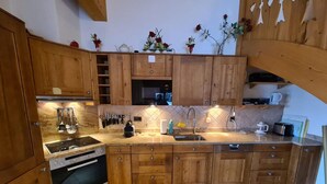 Une cuisine dotée de meubles en bois, d’une cuisinière, d’un four à micro-ondes, d’un évier et de divers ustensiles.