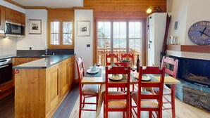 Une cuisine avec des meubles en bois, un four à micro-ondes et un coin repas comprenant des chaises rouges et une table.