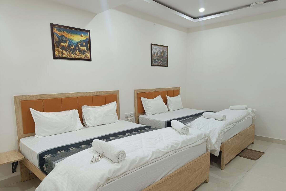 Een hotelkamer met twee bedden, een nachtkastje, een klein tafeltje en twee aan de muur bevestigde kunstwerken.