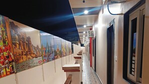 A corridor with benches, a patterned floor, and a wall with a mural. - Hotel Assi Retreat (Varanasi)