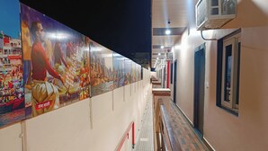 A corridor with a series of posters, a patterned floor, and a row of doors. - Hotel Assi Retreat (Varanasi)