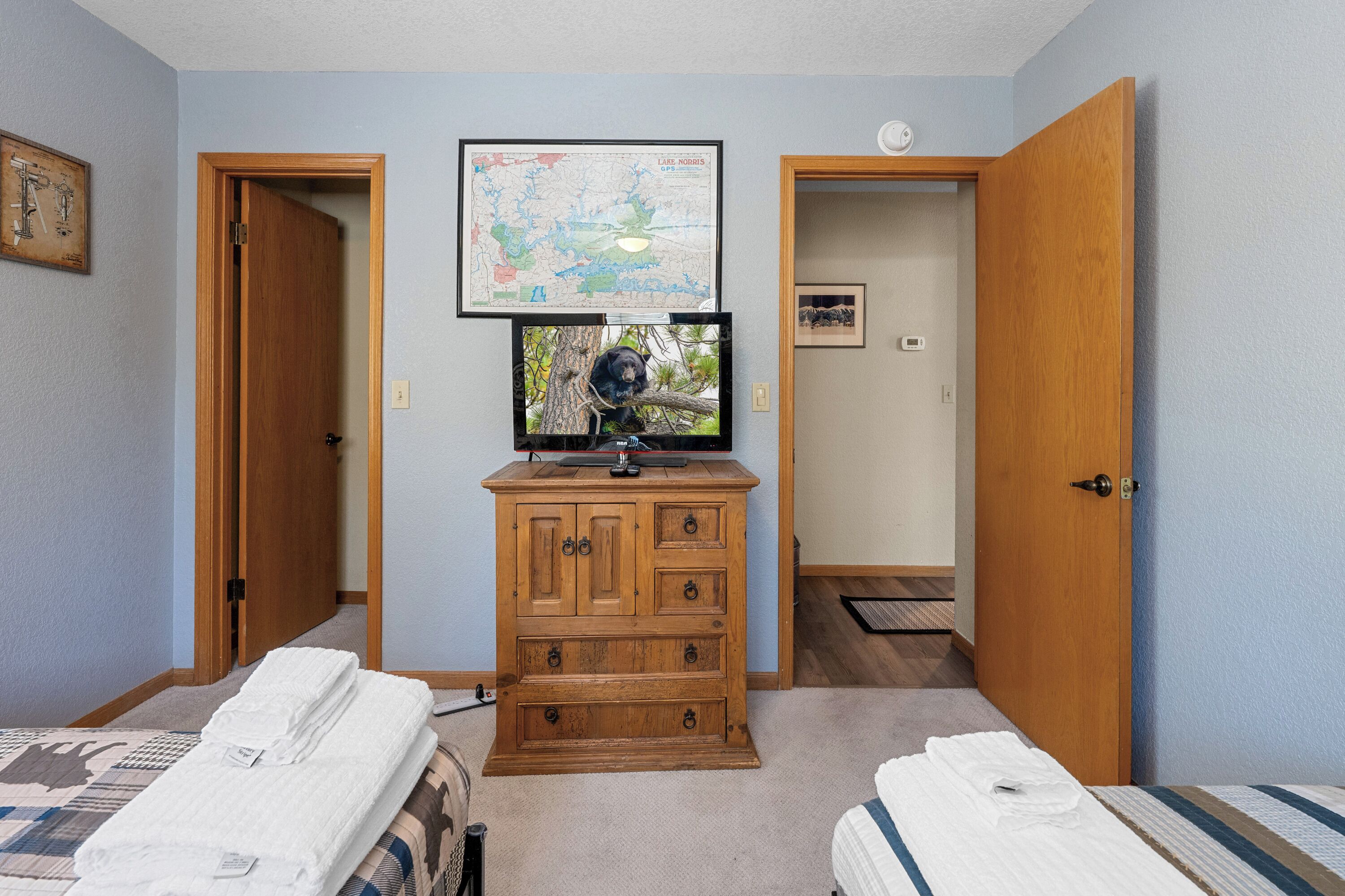 Un dormitorio con dos camas, un aparador, un televisor y un mapa en la pared.
