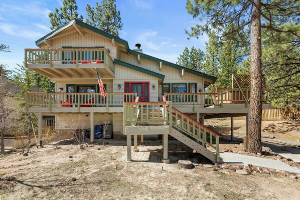 A two-story building with a balcony, a red door, and a staircase leading to the upper level. - Lakeview Haven- Luxury Retreat (Big Bear Lake)