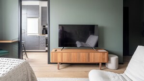 Een moderne slaapkamer met een televisie, een houten kast en een bed.