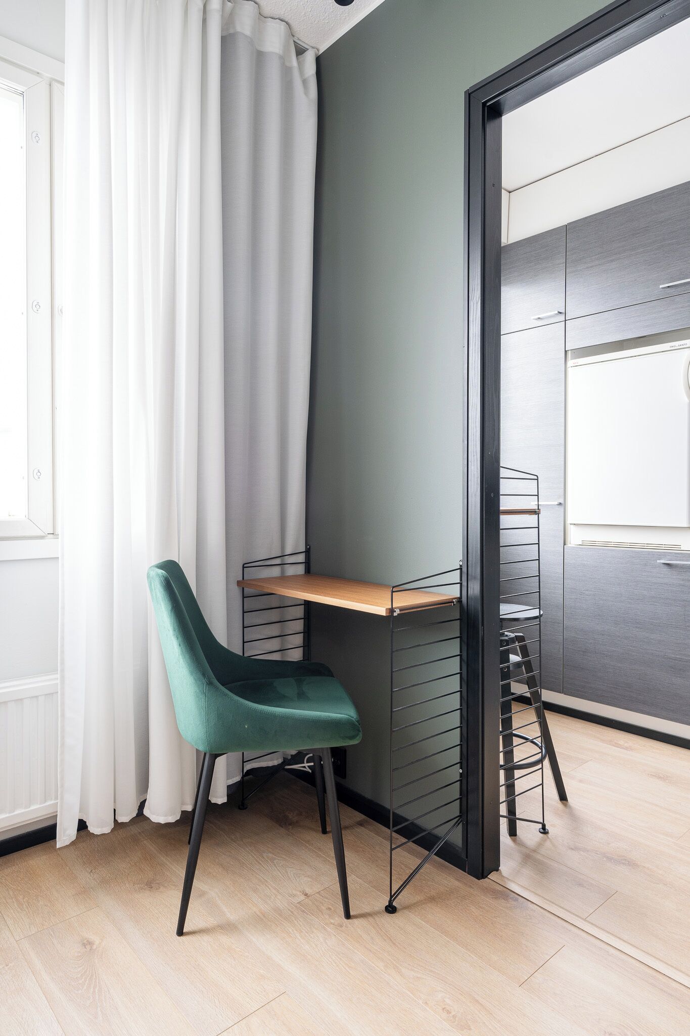 Una habitación con un escritorio, una silla, una ventana con cortinas y una puerta.