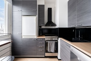 Una cocina moderna con horno empotrado, extractor de aire negro y lavavajillas.