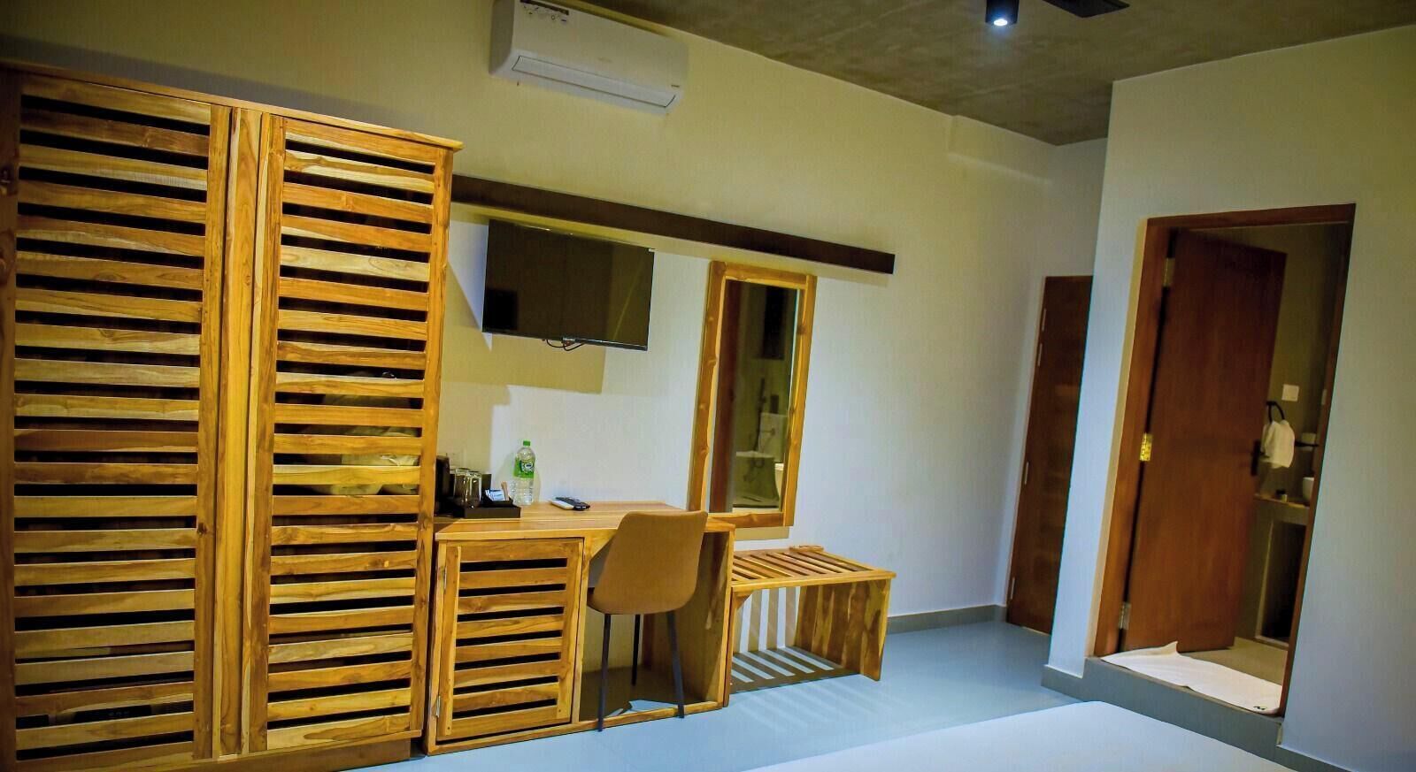 A room with a wooden desk, chair, and a TV mounted on the wall.