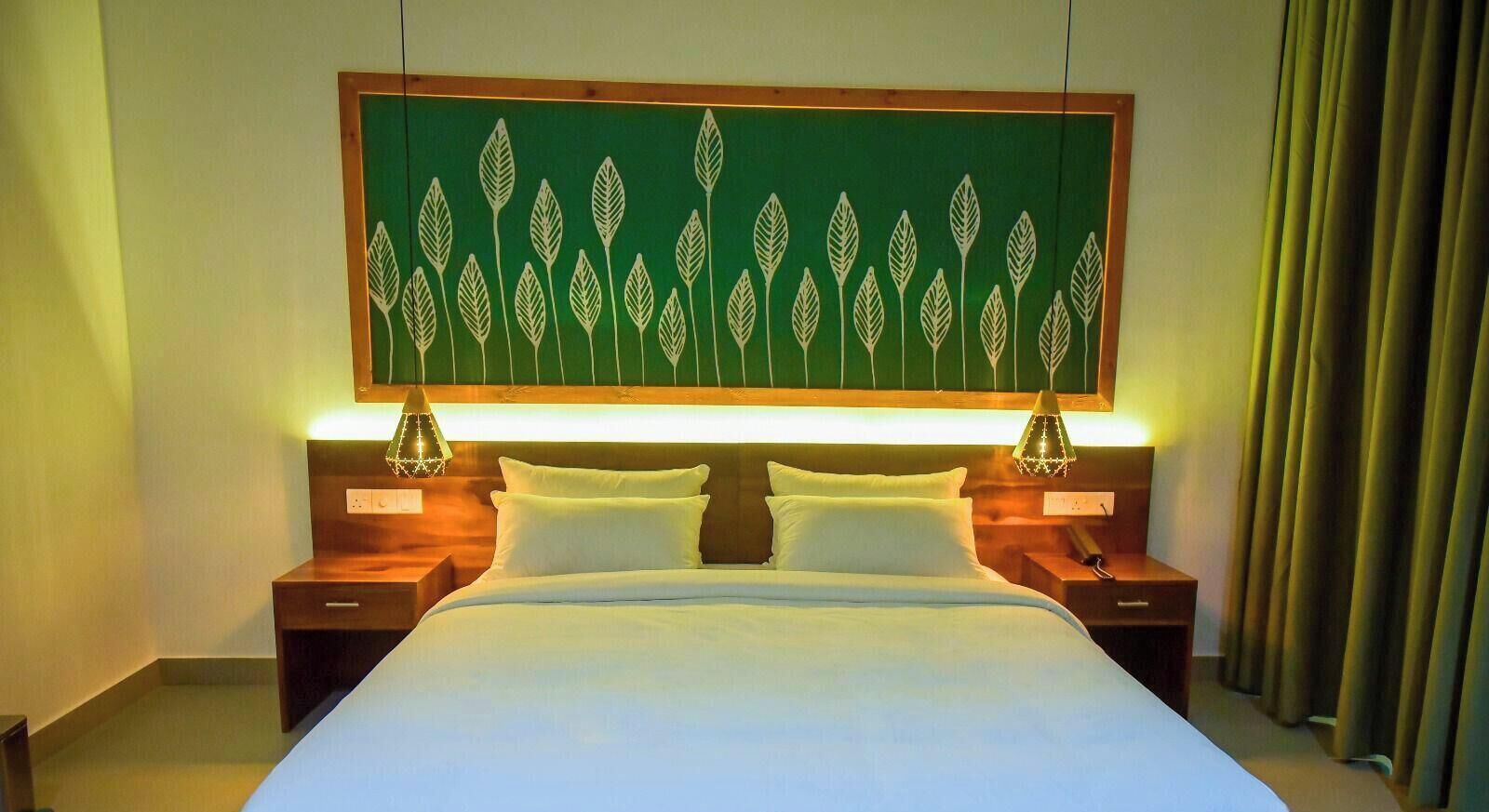 A hotel room with a bed, two bedside tables, a wall-mounted artwork, and a curtain.