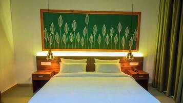 A hotel room with a bed, two bedside tables, a wall-mounted artwork, and a curtain.