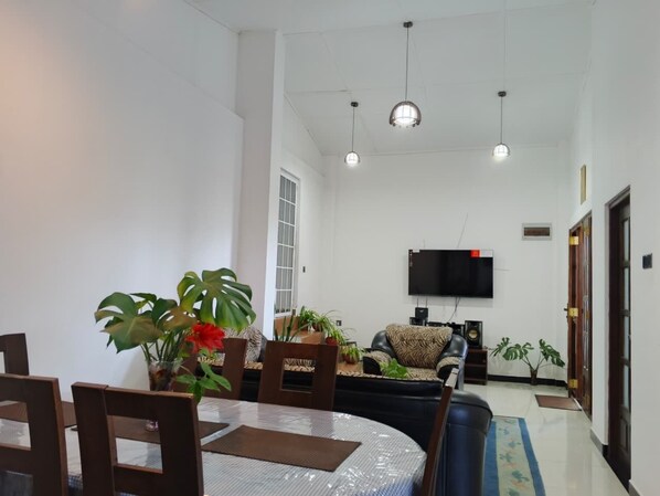 A dining area with a round table, chairs, and potted plants.