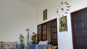 A living room with a sofa, a coffee table, a Buddha statue, and a clock on the wall.